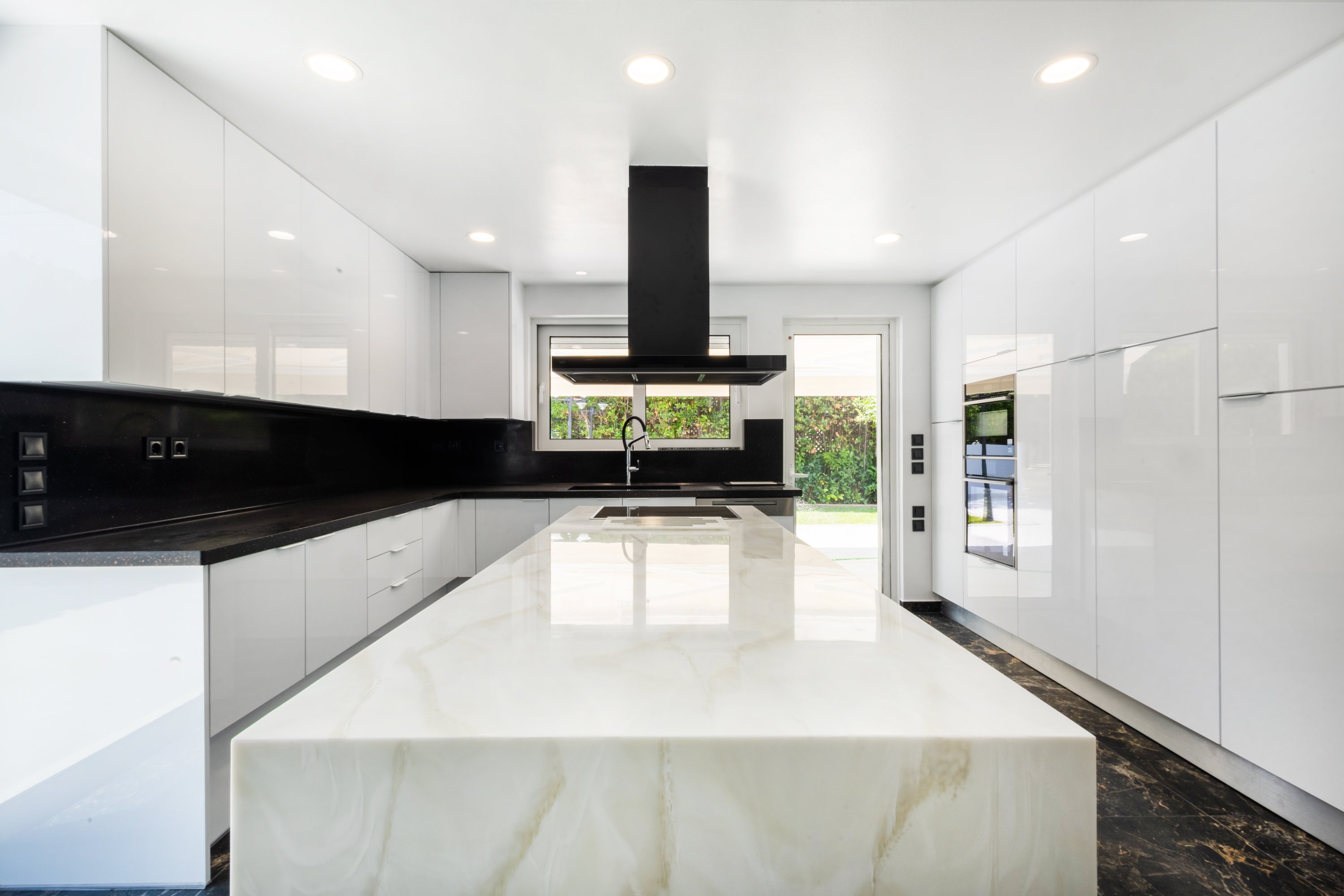Glossy monochrome kitchen with a pale stone waterfall island